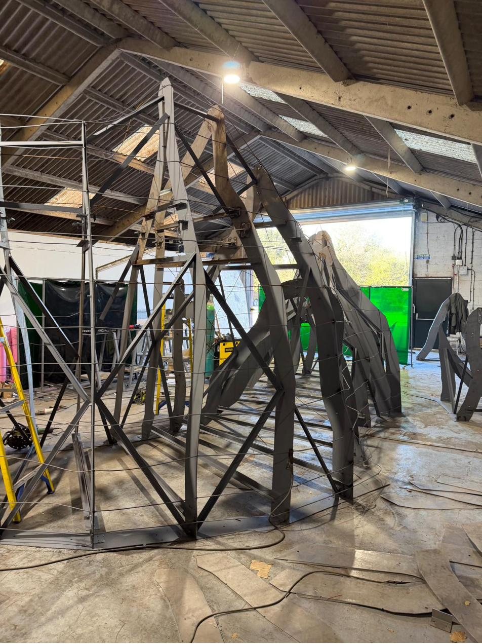 Steel armature rib frames braced and standing across the workshop floor