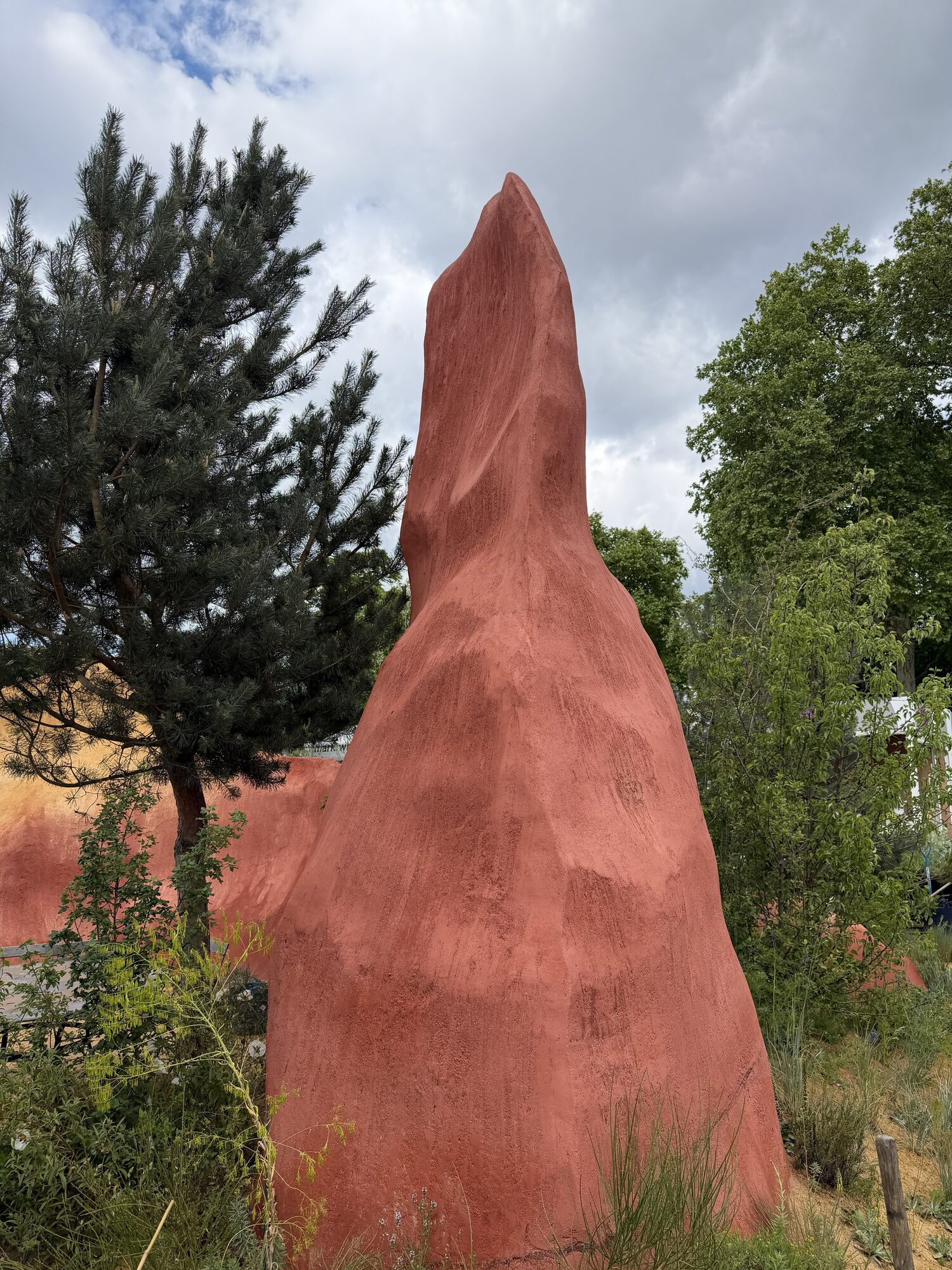 A finished red ochre sandstone form against cloudy sky