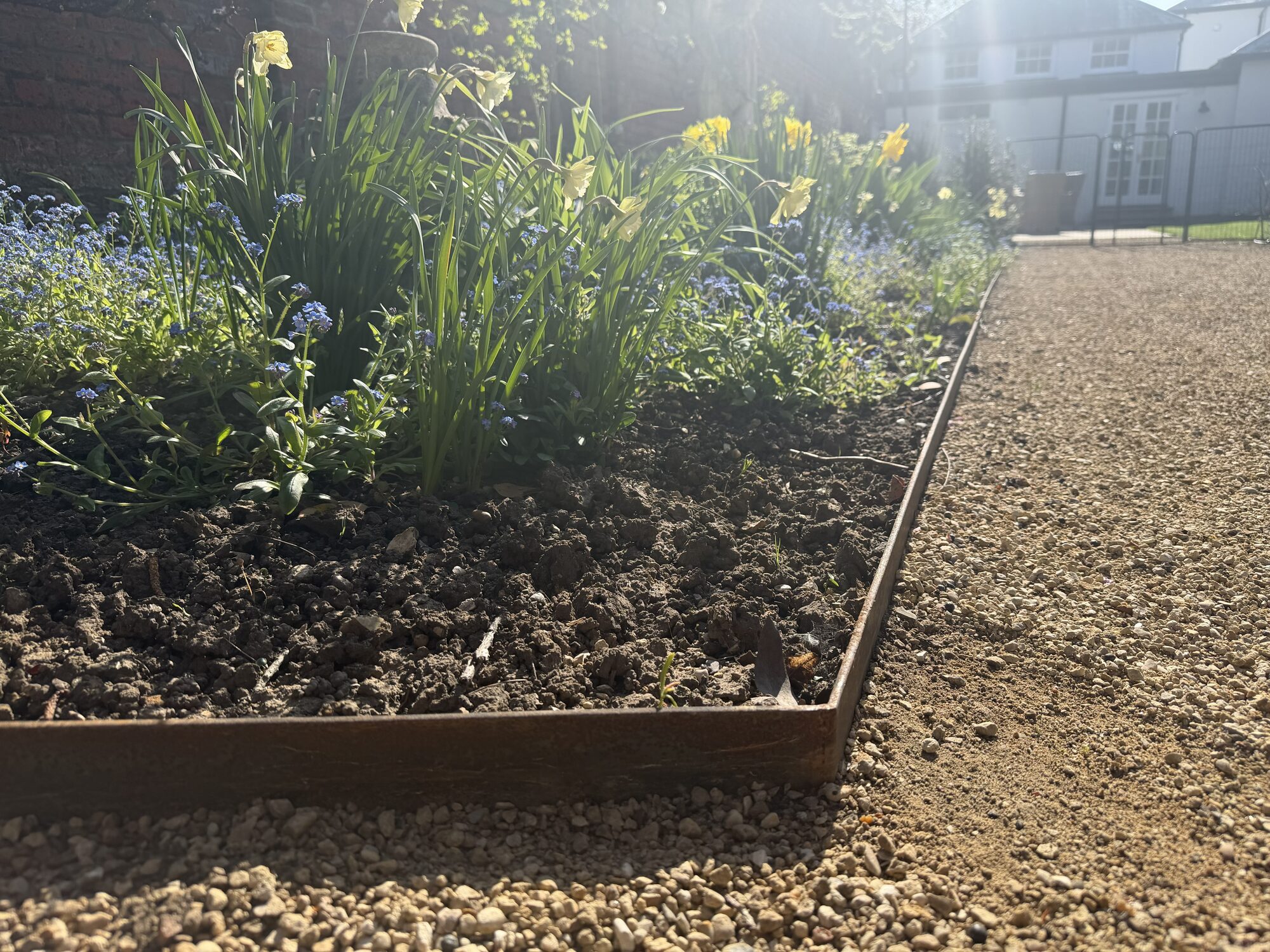 Hand-formed corten steel garden edging in a country house bed