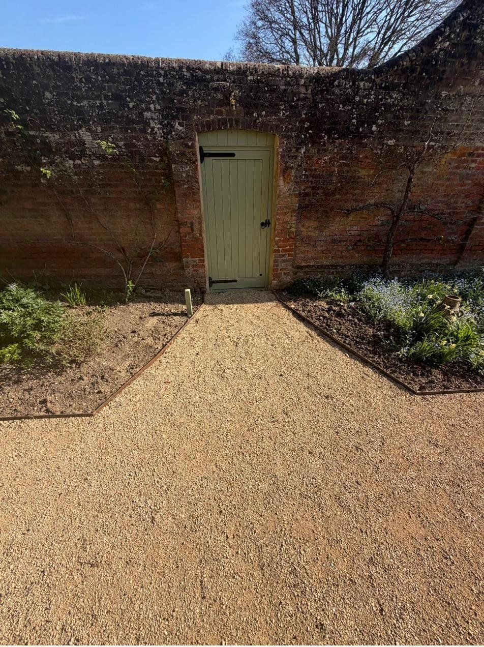 Steel-edged gravel path leading to a walled garden door